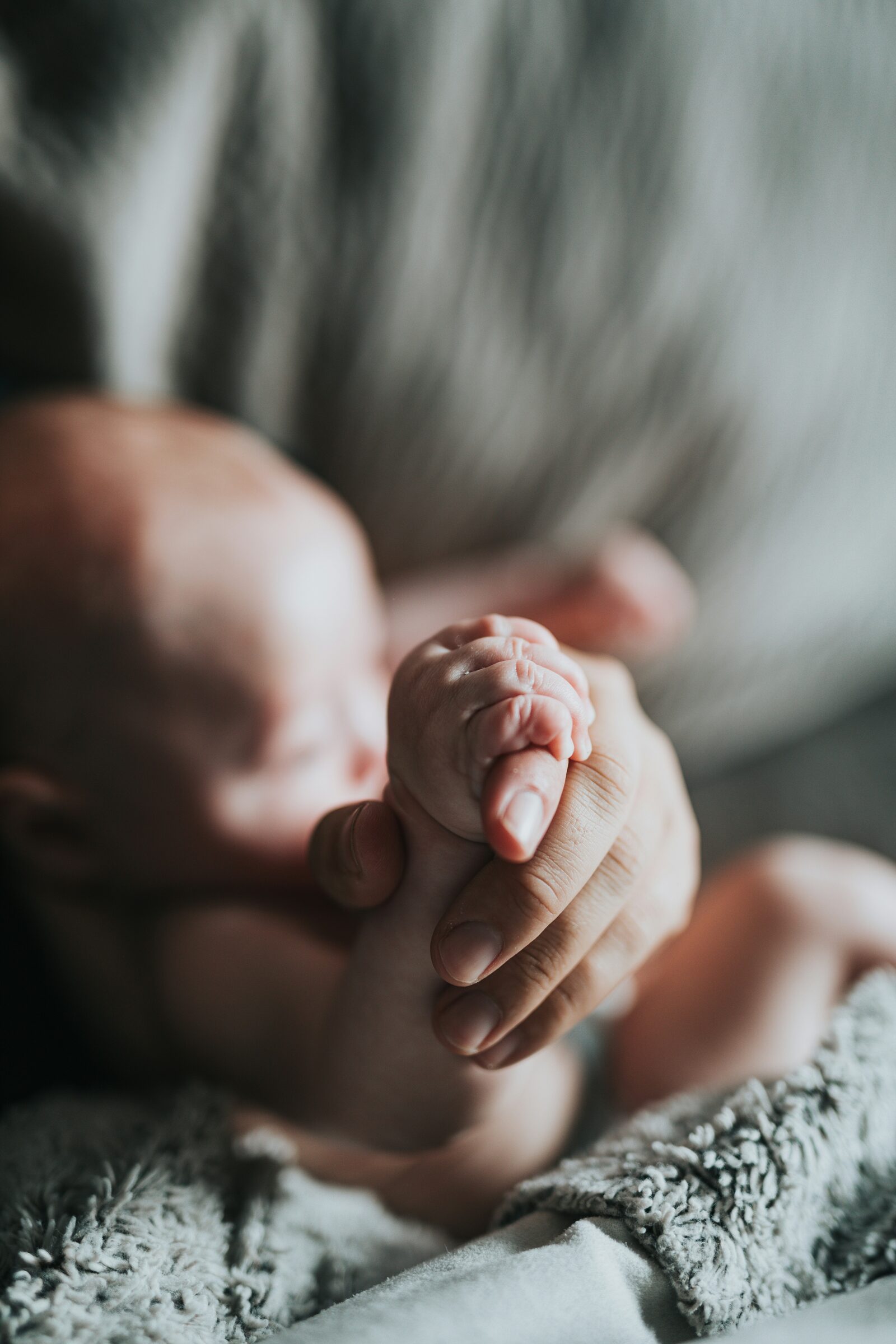 Mano de bebé recién nacido agarrando el dedo de su madre
